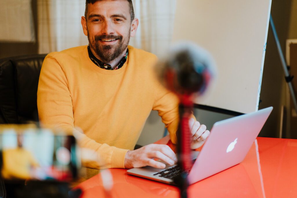 Alan from Yellow Tuxedo sat at a red desk downloading a fb live video to be repurposed