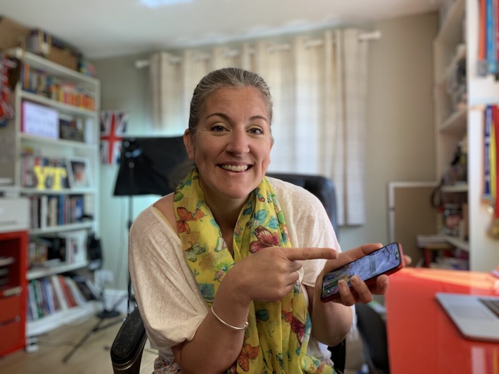 Emily from Yellow Tuxedo holding a red iPhone xr to demonstrate how to screen record with sound on an iPhone