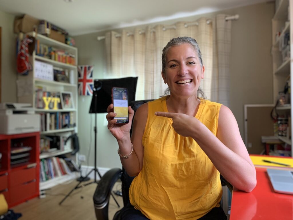 Emily shows you how to screen share on Instagram live in her office. She is holding a red iPhone XR