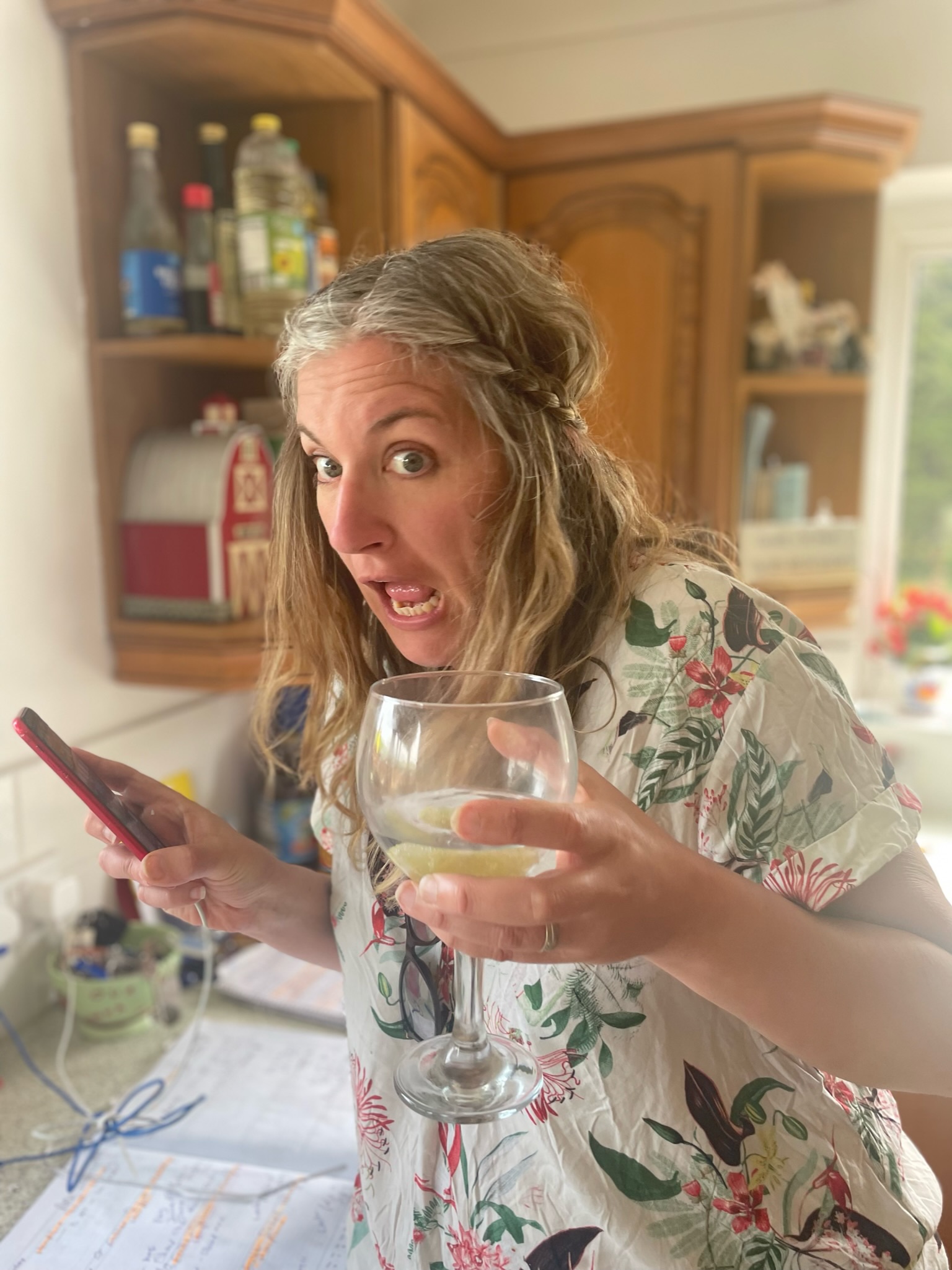 Emily from Yellow Tuxedo looking panicked whilst holding a gin and tonic in one hand and a mobile phone in the other.